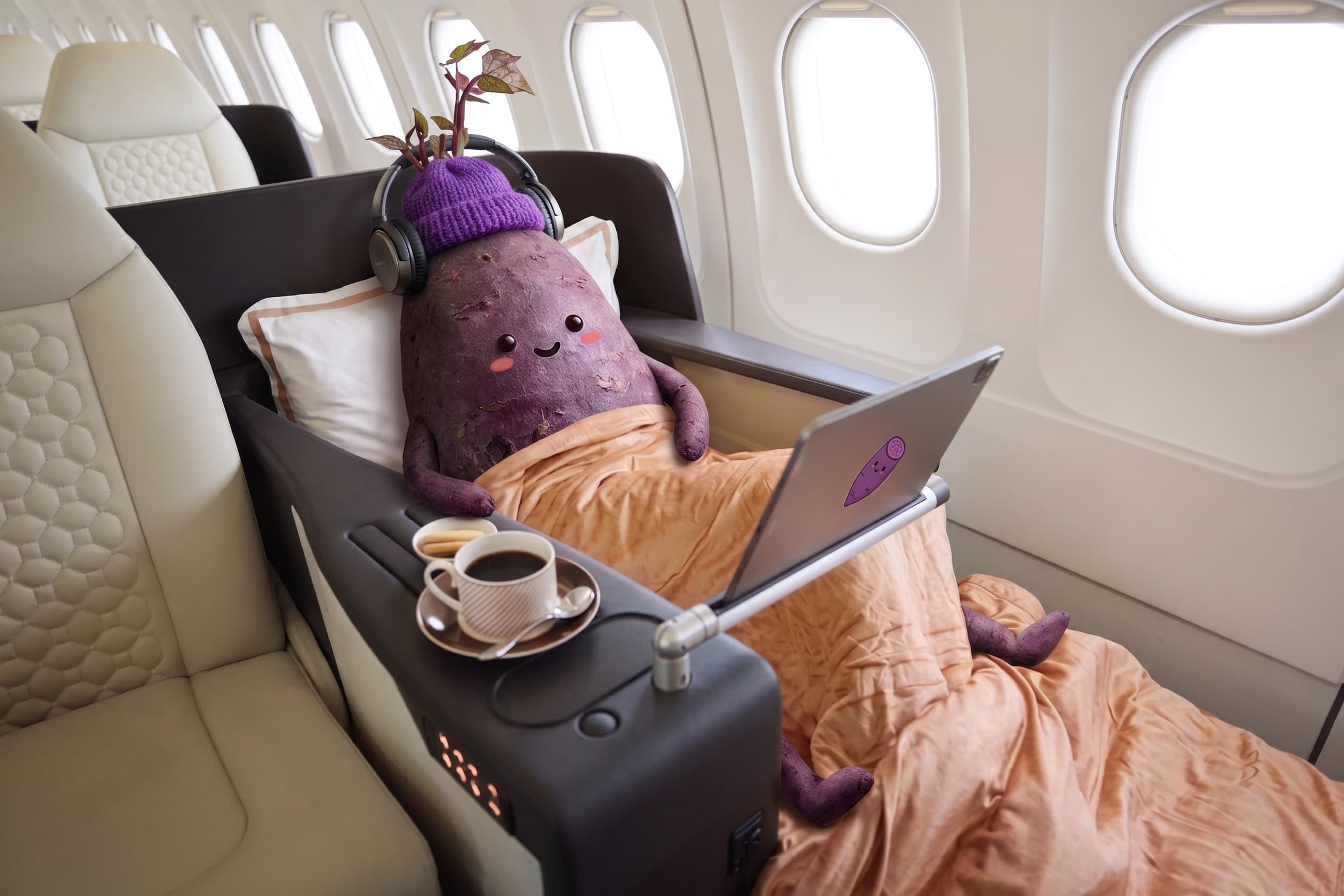 A plush purple yam in a beanie and headphones, reclining in an airplane seat with a laptop and a coffee